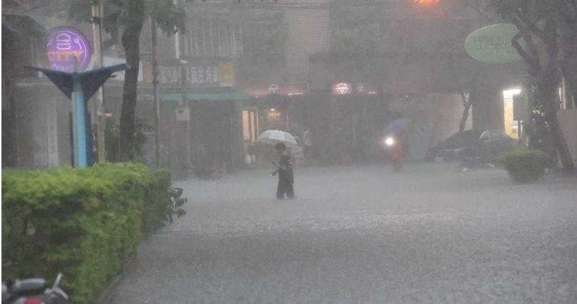 一位民眾涉水走過淹成小河的新北市永和國光街。（圖／民眾提供）