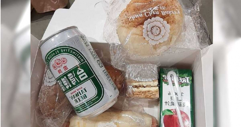 從曝光的照片中可見，餐盒中有數個麵包和一瓶鋁箔包裝的蘋果汁，以及常溫啤酒。（圖／翻攝自「匿名2公社」臉書）