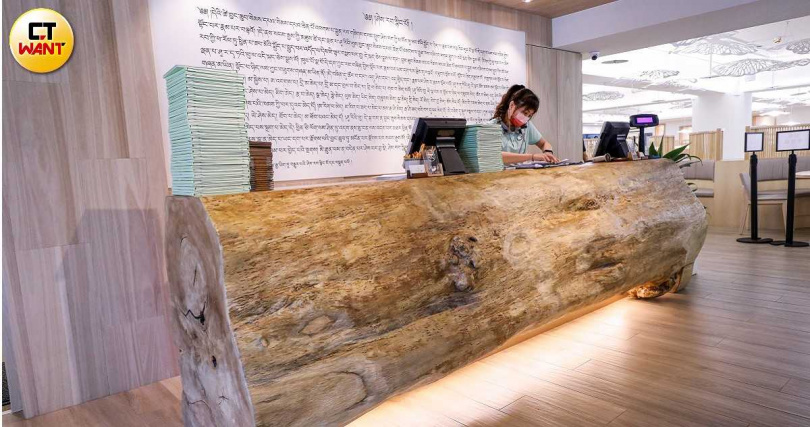 餐廳以千年菩提木製作櫃台帶出原始自然的意涵，牆上還刻有藏文心經。（圖／趙文彬攝）